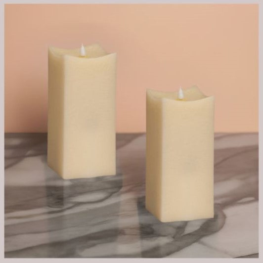 two 8" LED flameless ivory candles on marble countertop