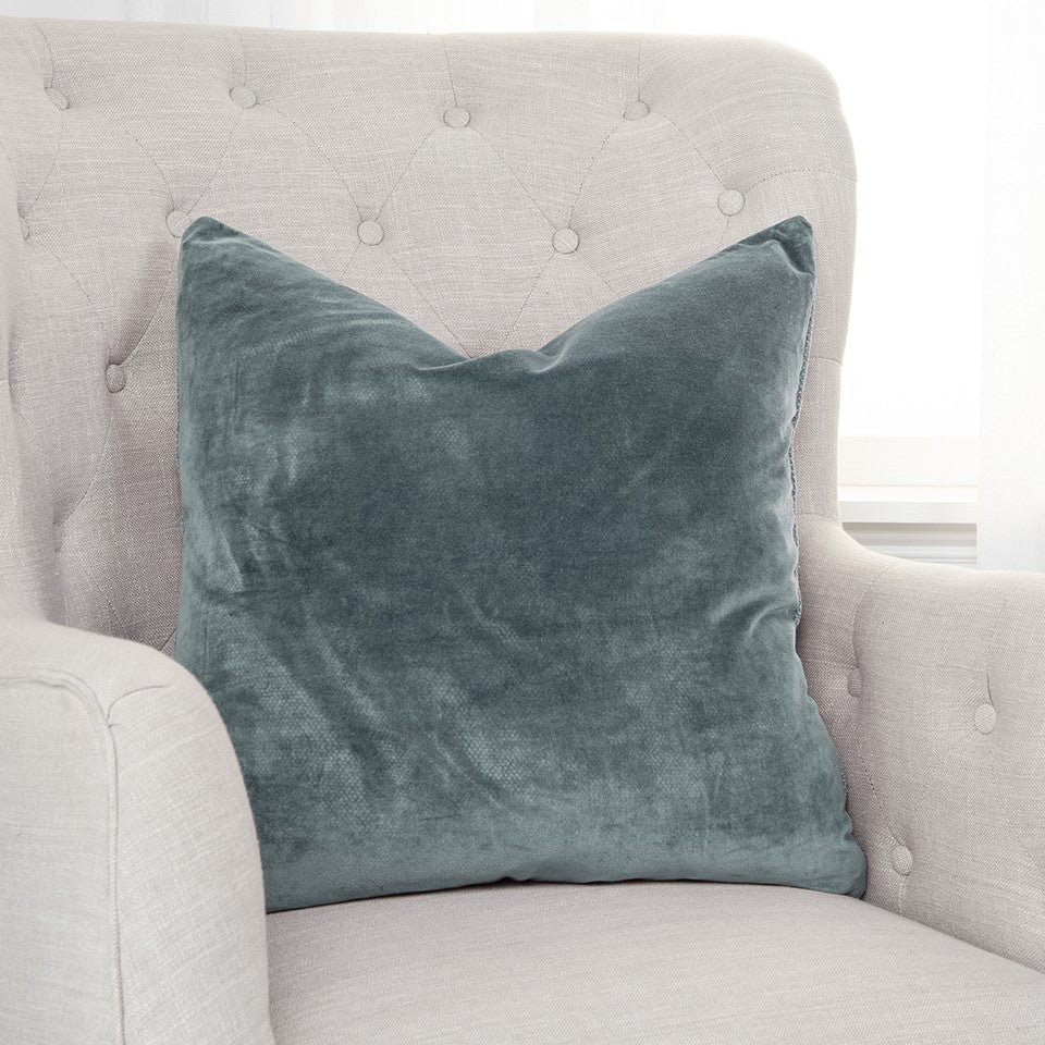 solid teal reversible cotton throw pillow 22" on cream chair