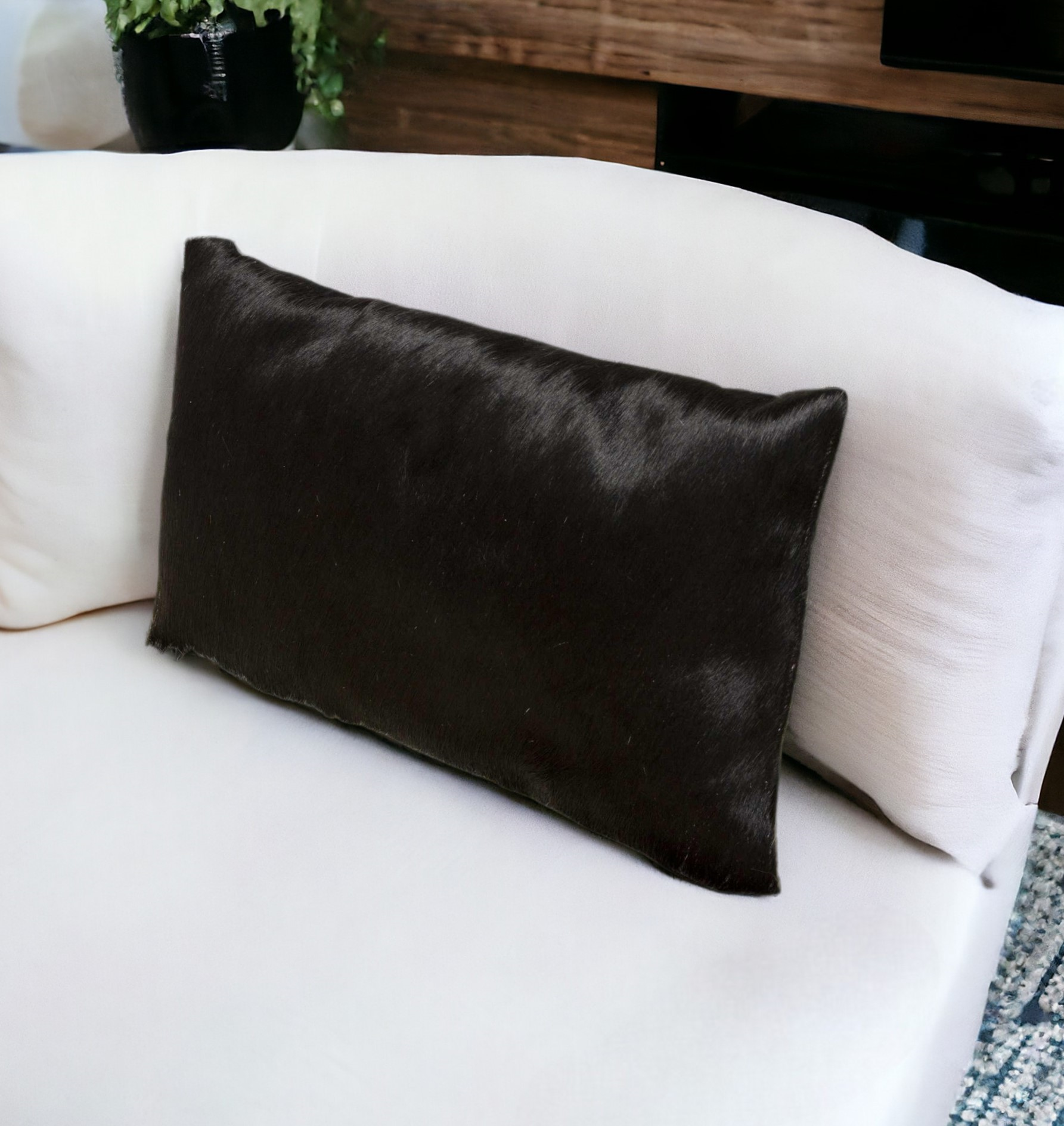 black cowhide lumbar throw pillow on white sofa