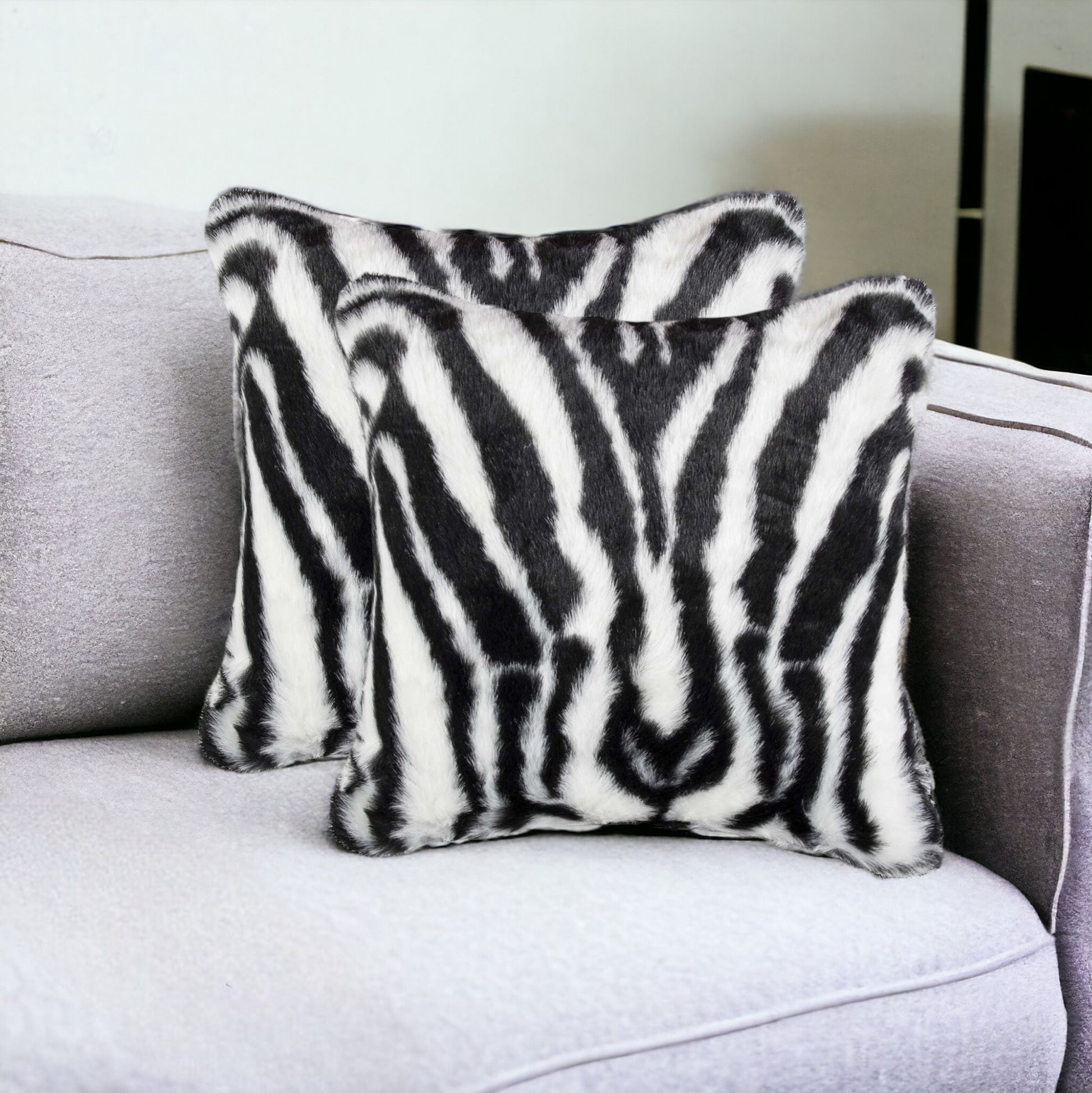 two 18" zebra pattern black and white throw pillows on lavender sofa