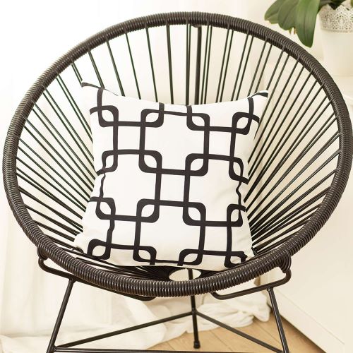 white 18 inch throw pillow with a black interlocking geometric pattern set on a wire metal chair